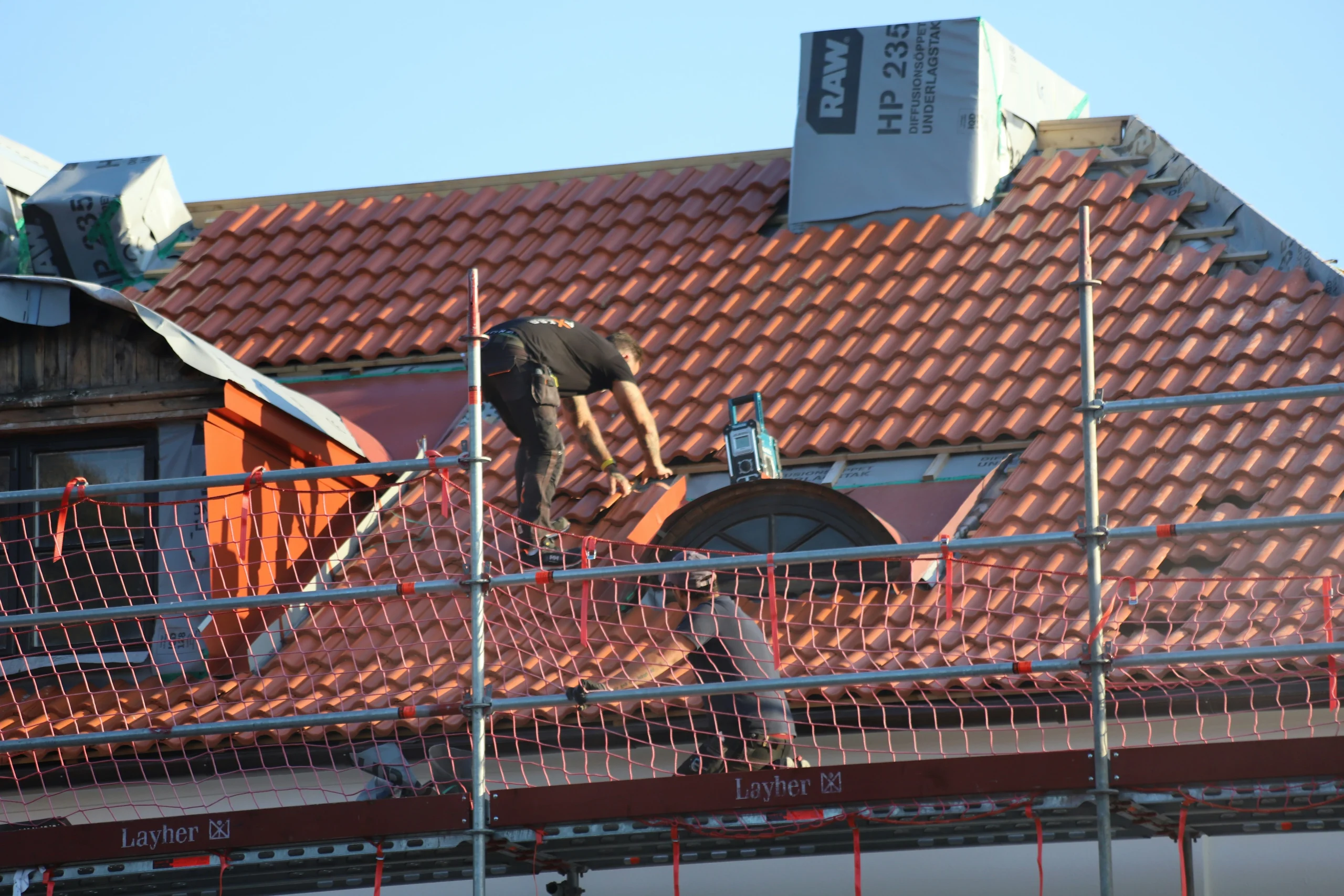 Construction workers working on roof tiles