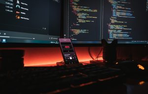 Mobile phone and three desktop computer screens showing mobile app development and testing process