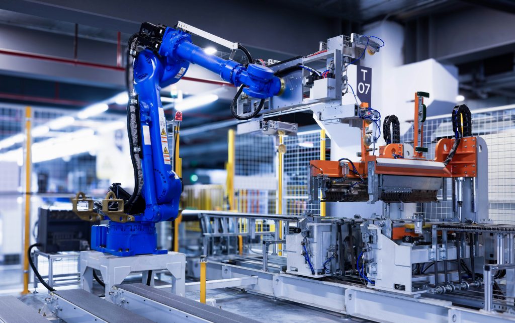 Blue industrial robotic arms on an automated manufacturing assembly line in a factory
