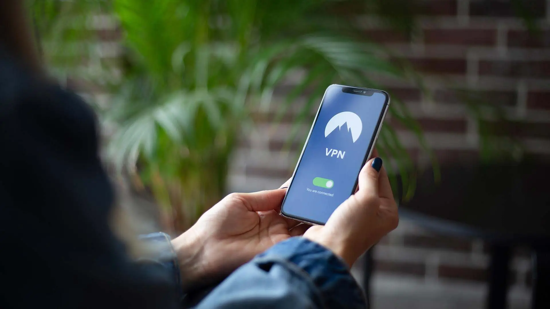 Hand holding smartphone displaying NordVPN app with active VPN connection