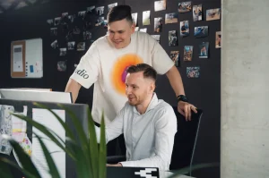 Two Softeta team members collaborating at a computer workstation in modern office