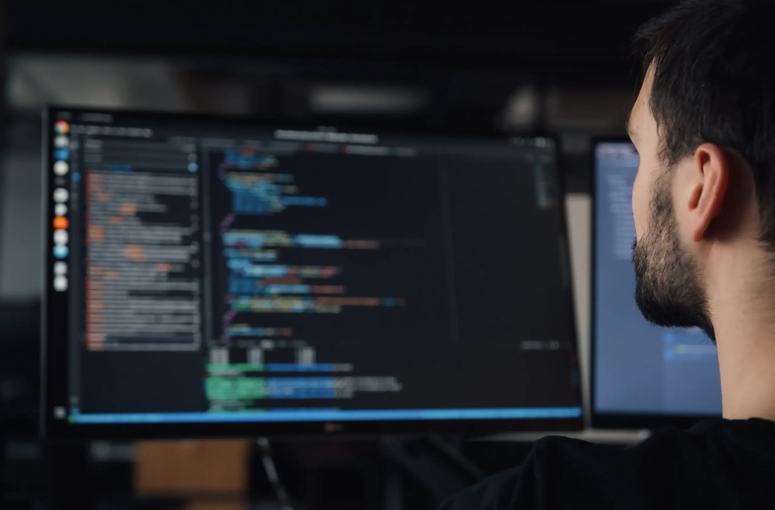 Software developer looking at code on computer screens