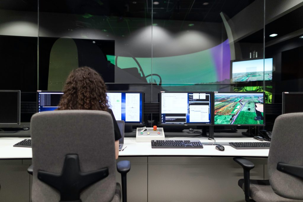 Engineer monitoring operations in a control room with multiple display screens showing system data