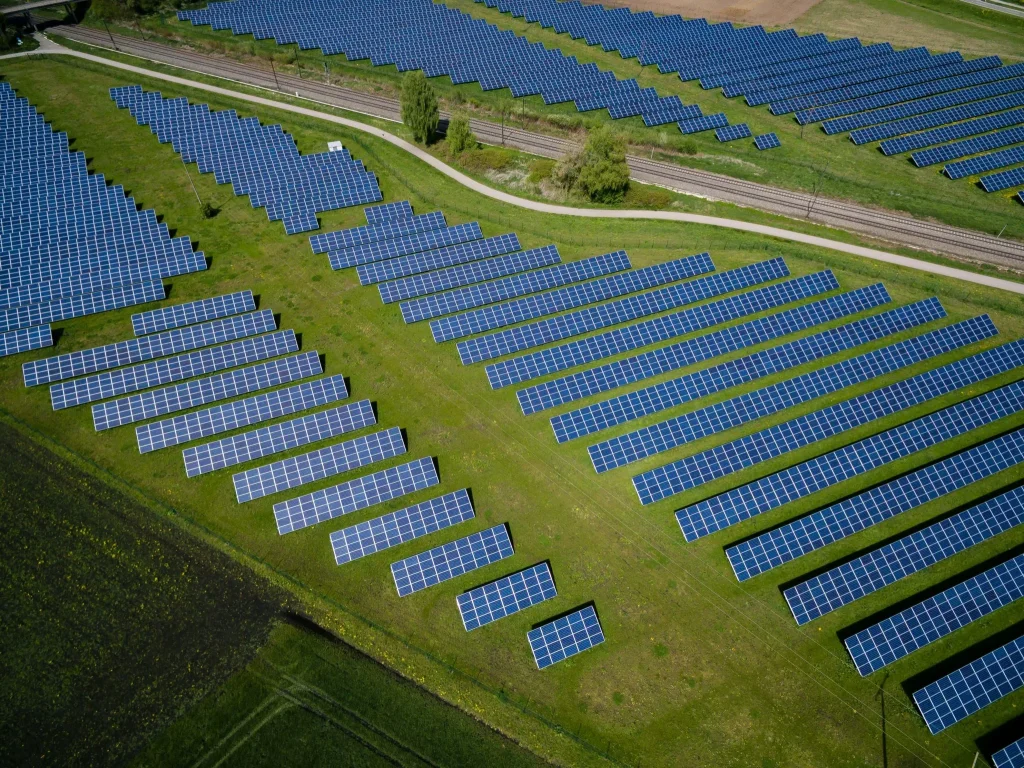 Aerial view of a large solar panel farm with rows of photovoltaic panels in a green field