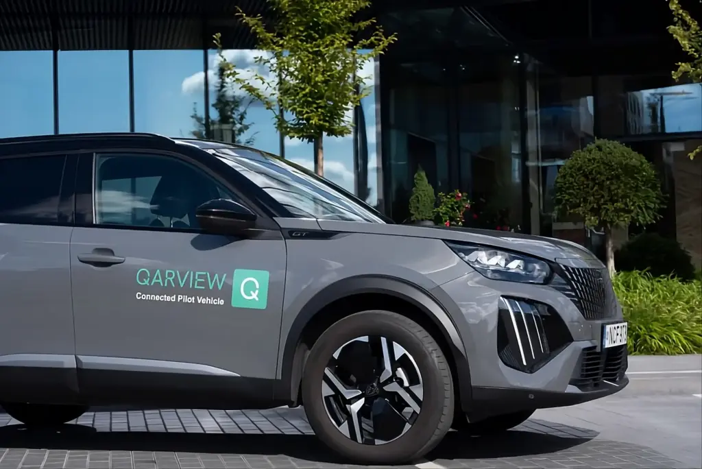 A photo of a grey Peugeot compact SUV with QarView logo, shot from the right side in an urban setting